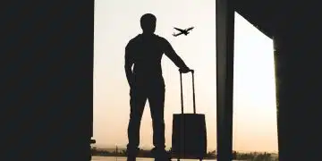 silhouette of man holding luggage inside airport