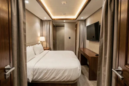 Cabine intérieure de croisière sans hublot avec lit double et bureau compact, décoration sobre en tons neutres