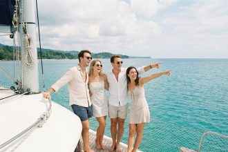 Groupe d'amis souriants sur un catamaran en mer turquoise