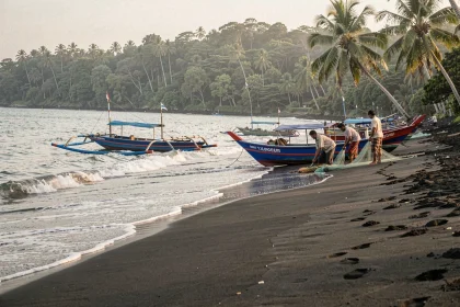 Plage de sable noir de Lovina à Bali avec des bateaux de pêche traditionnels Jukung colorés au bord de l'eau au lever du jour