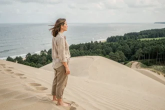 Femme contemplant la vue panoramique depuis le sommet de la Dune du Pilat avec l'océan Atlantique et la forêt landaise en arrière-plan